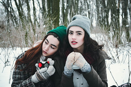 two women in jacket with knit hats on snow fields during daytime thumbnail