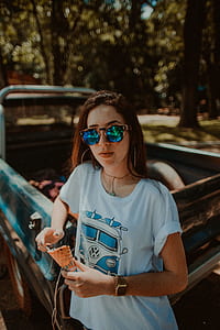 woman leaning on blue single cab while carrying an ice cream cone during daytime thumbnail