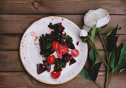 sliced beet and tomatoes on ceramic plate beside white flower thumbnail