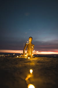 mannequin with string lights sitting on gray dirt thumbnail
