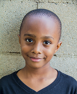 boy smiling leaning on wall wearing black shirt thumbnail
