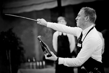Grayscale Of Man Holding Sword And Bottle thumbnail