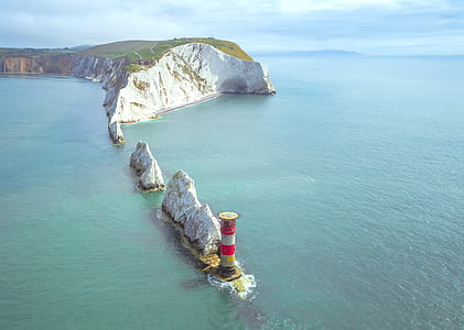 aerial photo of red and white lighthouse beside body of water thumbnail
