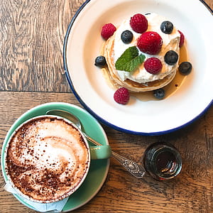 top view of pancakes with whip cream , strawberries and blueberries on top thumbnail