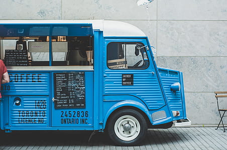 blue and white coffee truck parked near white cement wall during daytime thumbnail