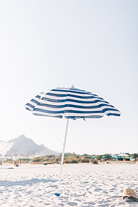 white and blue striped patio umbrella on seashore thumbnail