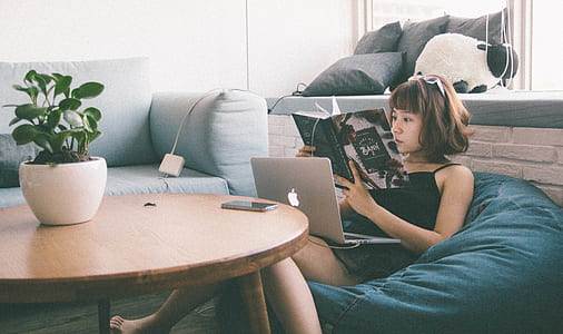 Woman Sitting on Bean Bag White Using Macbook in Front of Round Table With Green Leafed Plant thumbnail