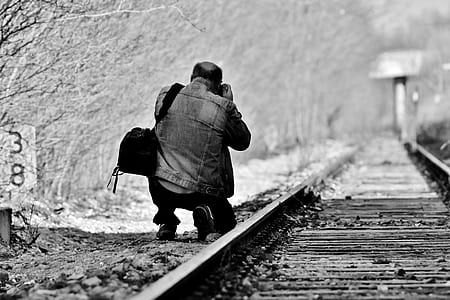 man kneel on trail railway holding camera thumbnail