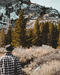 man standing near green pine trees thumbnail