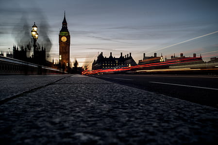time-lapse photo of vehicle passing the road with a view of big ben under gray sky thumbnail