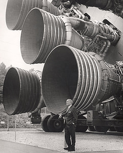 grayscale photography of man standing near metal machine during daytime thumbnail
