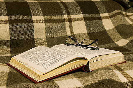 opened book with black framed eyeglasses on top thumbnail