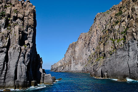 rock formation beside body of water during daytime thumbnail