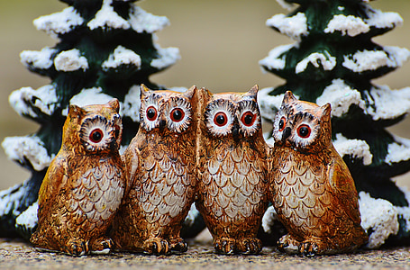 family of four wooden owl sculptures with pine trees behind thumbnail