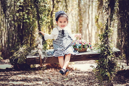 Girl in Black and White Overall Skirt Holding Basket With Petaled Flowers thumbnail