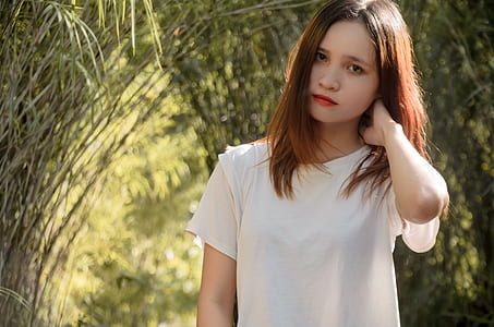 woman in white crew-neck shirt standing near green grass during daytime thumbnail