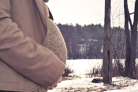 pregnant woman wearing brown coat standing on snow thumbnail
