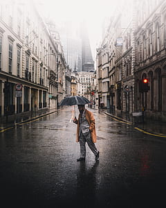person holding umbrella while walking on road during daytime thumbnail