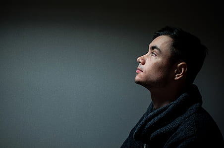 man wearing black coat beside white wall thumbnail