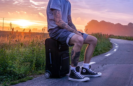 man wearing black Converse All-Star high-tops and black softside luggage bag thumbnail