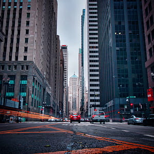 red vehicle between high rise building thumbnail