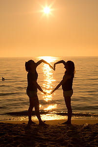silhouette of two women forming heart during golden hour thumbnail
