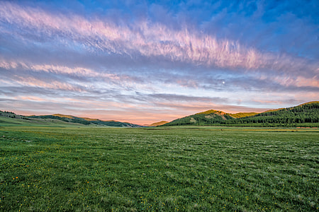 green field with mountains under blue sky thumbnail