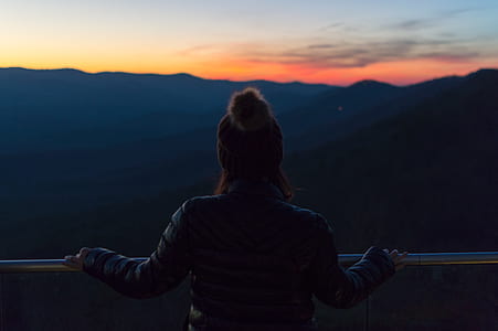 woman facing silhouette of mountain during golden hour thumbnail