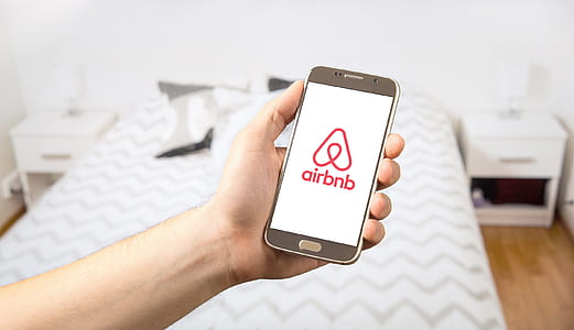 person holding smartphone displaying Airbnb logo thumbnail