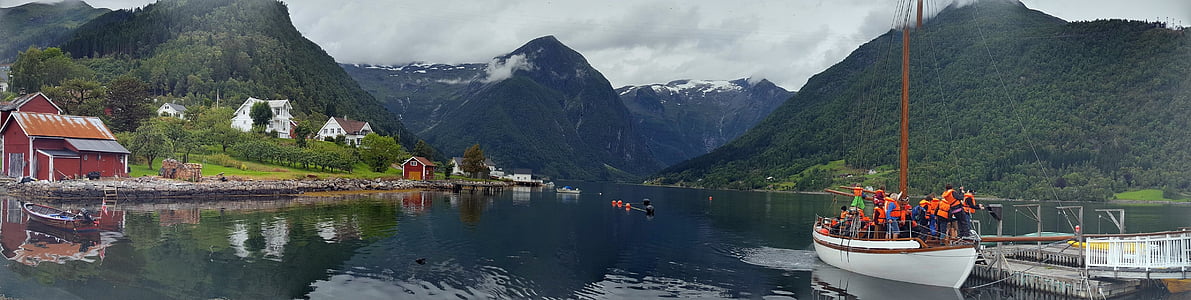 people on white boat beside dock overlooking hills at daytime thumbnail
