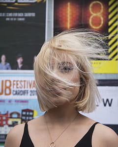 Woman With Flipping Hair Standing Near Poster thumbnail