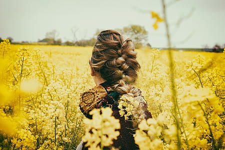 woman sitting in front of yellow petaled flowers thumbnail