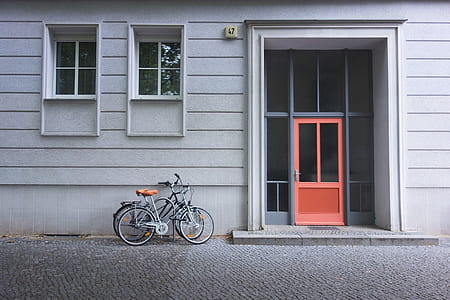 two gray and black bicycles beside wall near windows thumbnail