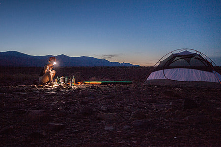woman wearing hard hat with flashlight near dome tent during nighttime thumbnail