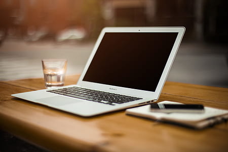 MacBook beside drinking glass on wooden table thumbnail