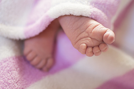 macro photography of baby's feet under pink blanket thumbnail