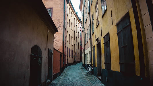 road between brown and black concrete houses under white sky at daytime thumbnail