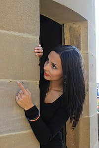 woman in black scoop-neck long-sleeved dress beside brown concrete wall thumbnail