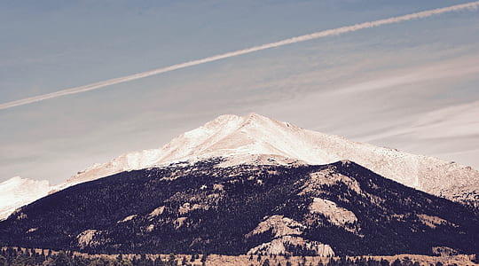trees near mountain under cloudy sky thumbnail