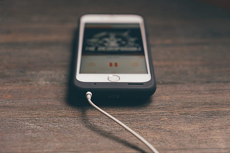 turned on iPhone displaying music on brown wooden surface thumbnail
