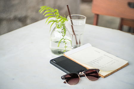 black Clubmaster-framed sunglasses beside book on white tablecloth thumbnail