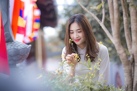 Woman Wearing White Long-sleeved Top Holding the Flower thumbnail