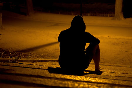 silhouette of person sitting on pathway during nighttime thumbnail