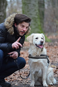 adult cream golden retriever sitting next to man in blue parka jacket in forest during day thumbnail