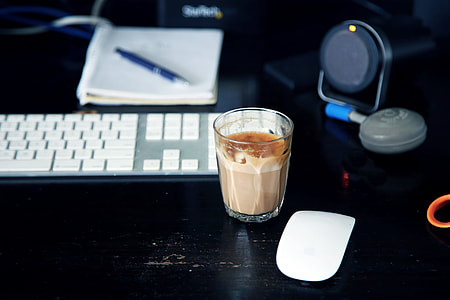 clear drinking glass filled with brown liquid near Apple machine keyboard and mouse thumbnail