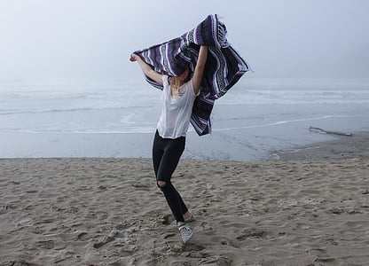 smiling woman dancing on seashore during daytime thumbnail