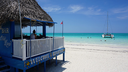 blue and white hut on beach in distant of boat on sea thumbnail