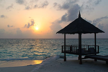 silhouette photo of gazebo near sea during golden hour thumbnail