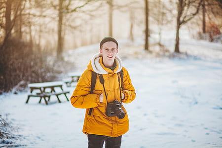 man wearing orange winter jacket standing on snowfield thumbnail