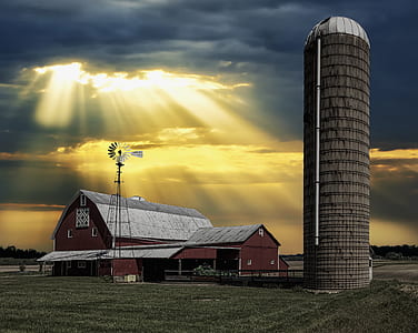 brown house and barn near silo during golden hour thumbnail